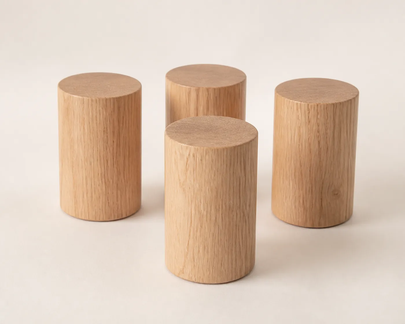 Quatre pieds de lit cylindriques en chêne clair sur une surface claire