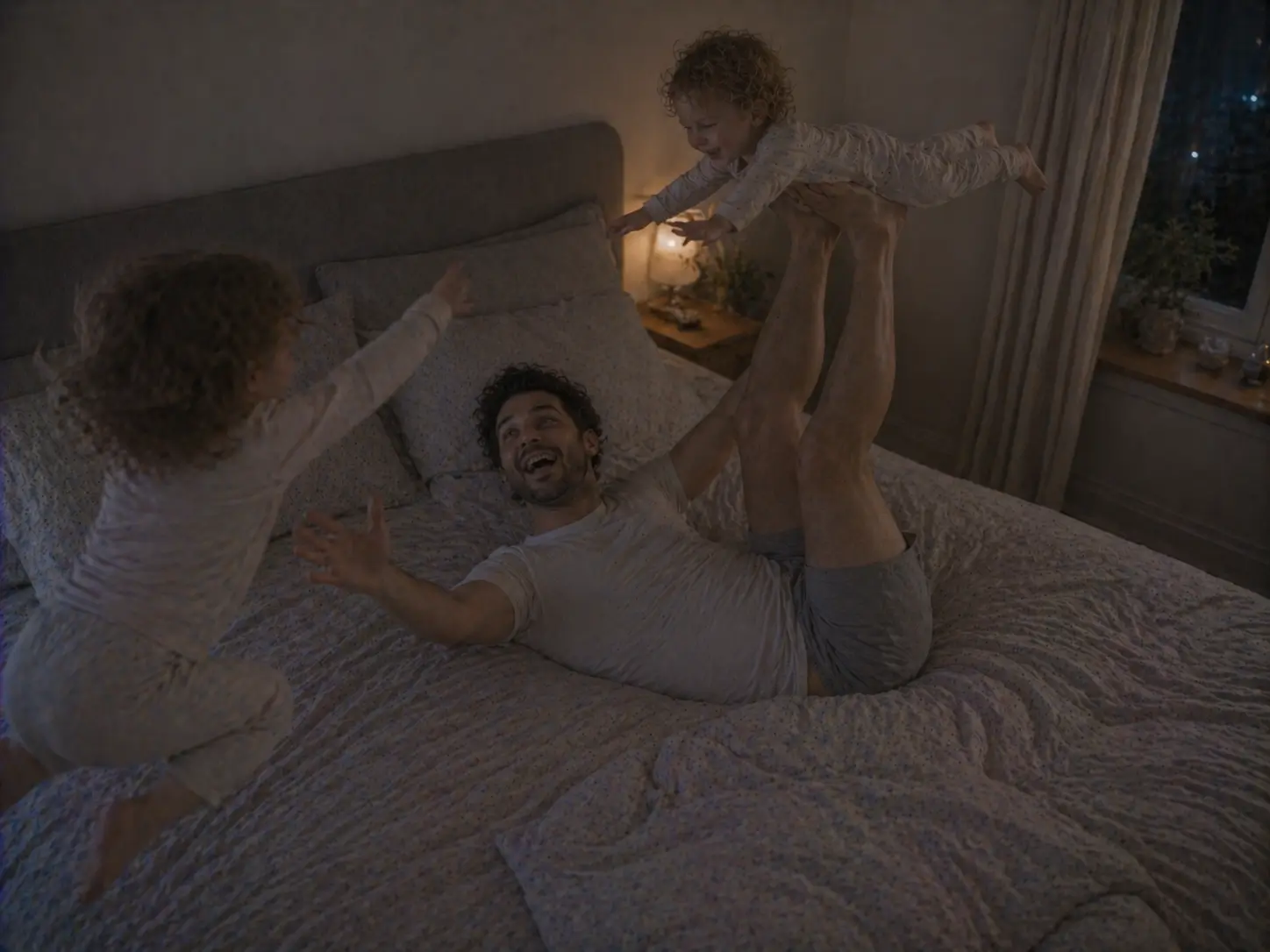 Un père fait l'avion avec l'un de ses enfants sur le lit, tandis que l'autre saute à côté