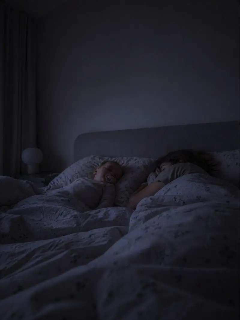 Des parents et leur enfant dorment blottis les uns contre les autres dans un lit, sous une douce lumière nocturne