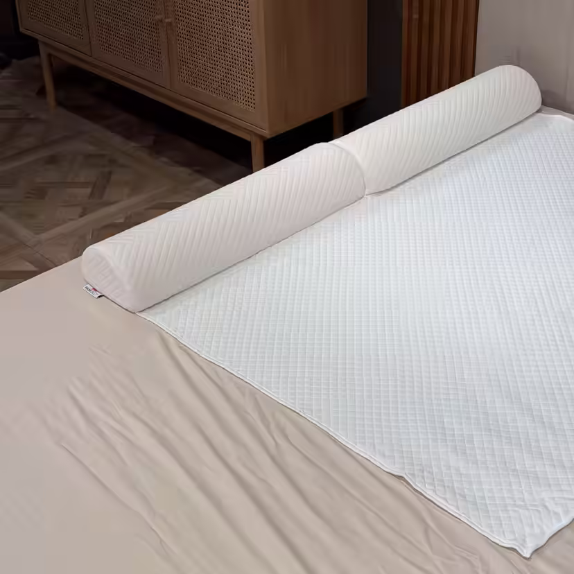 Barrière de lit matelassée en mousse installée sous la housse blanche du surmatelas, le long du bord du lit