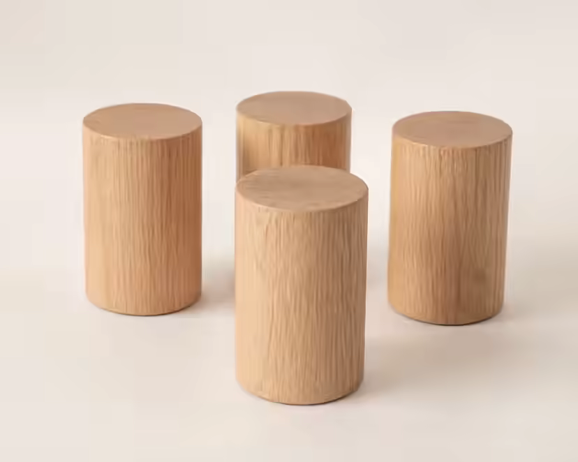 Quatre pieds de lit cylindriques en chêne clair sur une surface claire